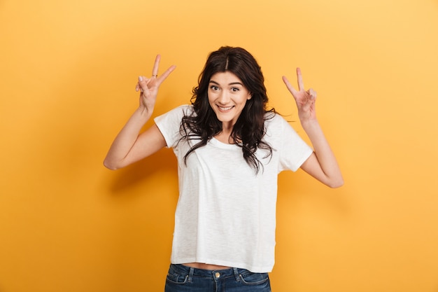 Cheerful young pretty woman showing peace gesture.