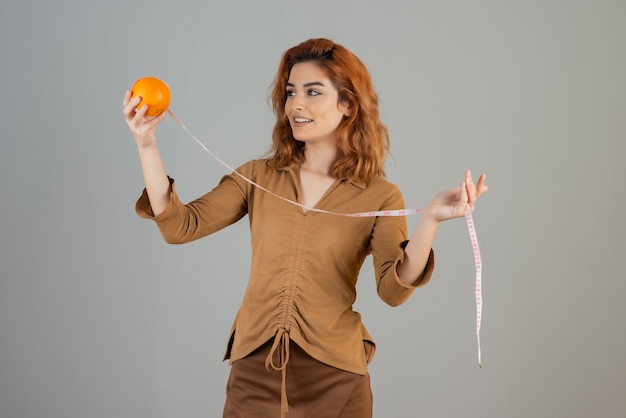 Cheerful young redhead with orange and measure in grey.