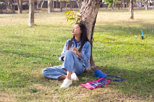 Foto giovane allegro seduto nel parco che disegna giacca e jeans picturewears concetto di vita cittadina
