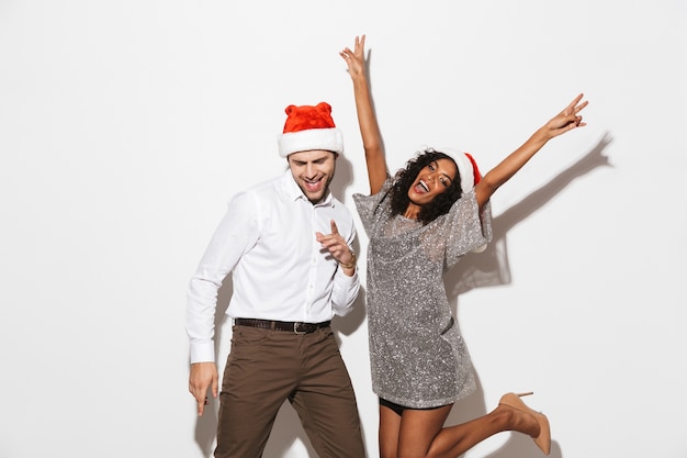 Cheerful young smartly dressed couple celebrating New Year isolated over white space