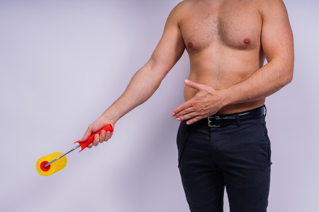 Photo cheerful young topless man hold paint roller isolated on a grey background studio