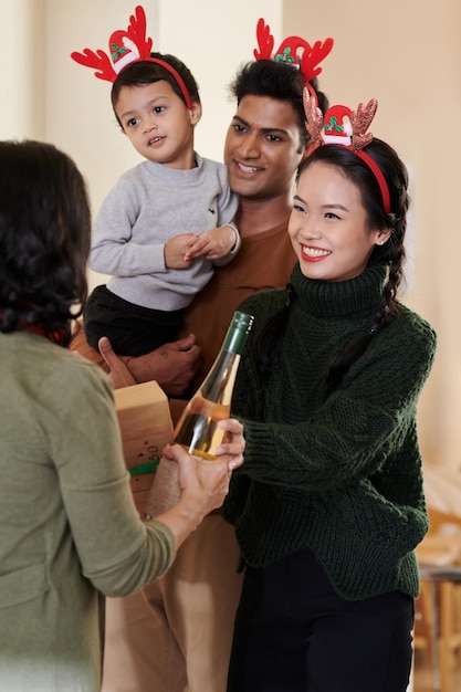 Photo cheerful young woman accepting present and wine her senior mother brought for christmas