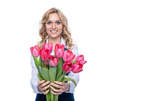 Cheerful young woman in apron with spring tulip flowers isolated on white background