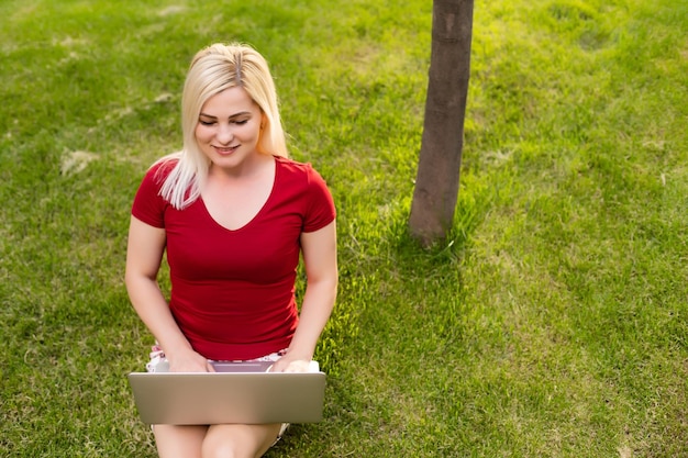 공원에서 야외에서 노트북으로 인터넷을 검색하는 쾌활한 젊은 여성