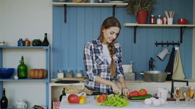 Cheerful young woman cooking breakfast in the kitchen early morning