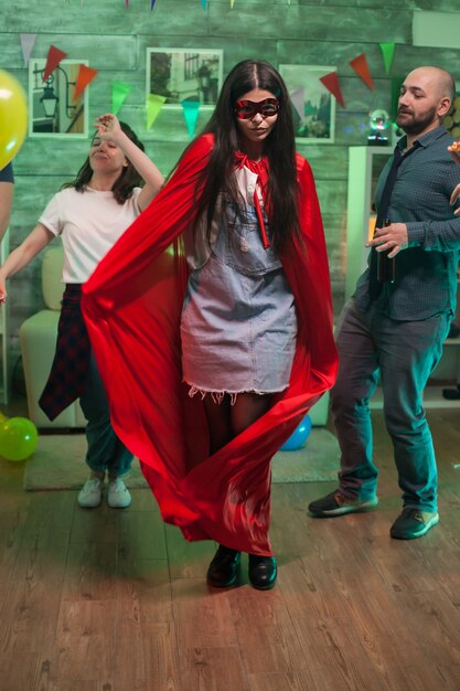 Foto allegra giovane donna vestita come un supereroe alla festa di amici.