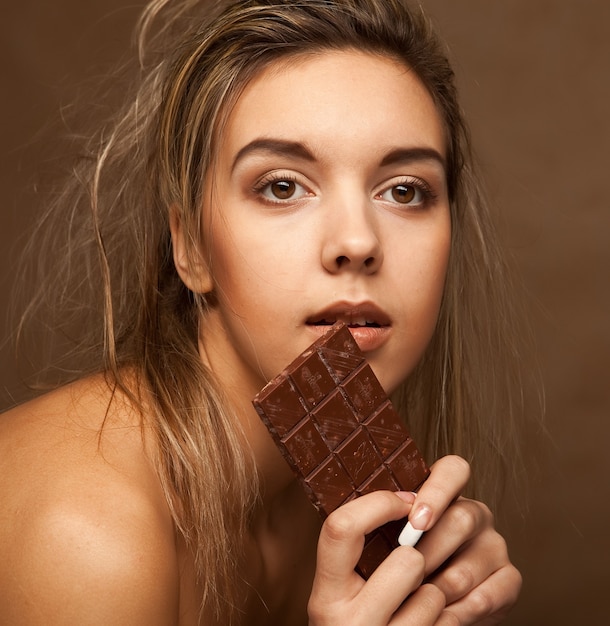 Веселая молодая женщина ест шоколад