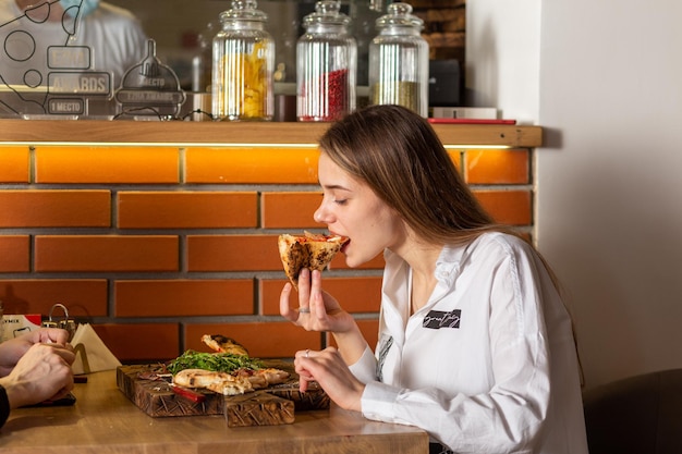 Giovane donna allegra che gode della fetta di pizza