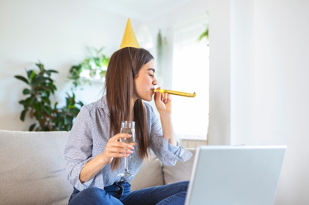 Giovane donna allegra che ha un evento di festa di compleanno con un amico durante una videochiamata.