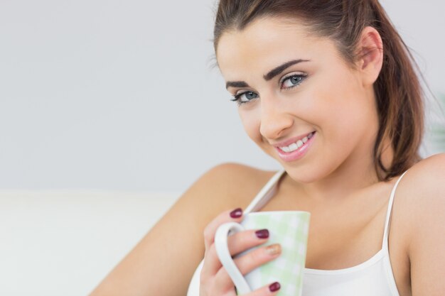 Cheerful young woman holding a cup 