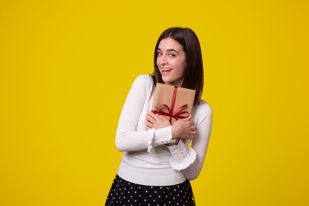 Cheerful young woman holding a gift looking at the camera.