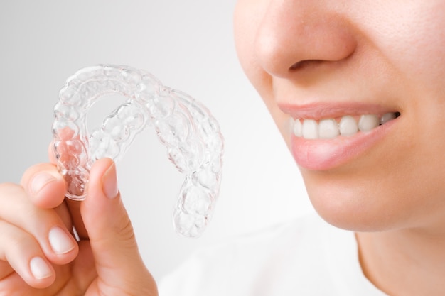 Photo cheerful young woman holding plastic transparent braces