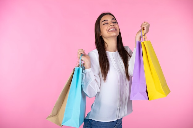 사진 쾌활 한 젊은 여자는 구매 가방을 보유하고있다. 다채로운 쇼핑 봉투와 함께 즐거운 유행 소녀