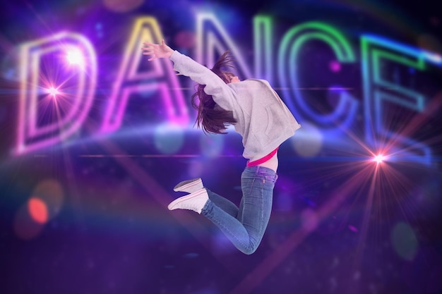 cheerful young woman jumping against digitally generated colourful dance text