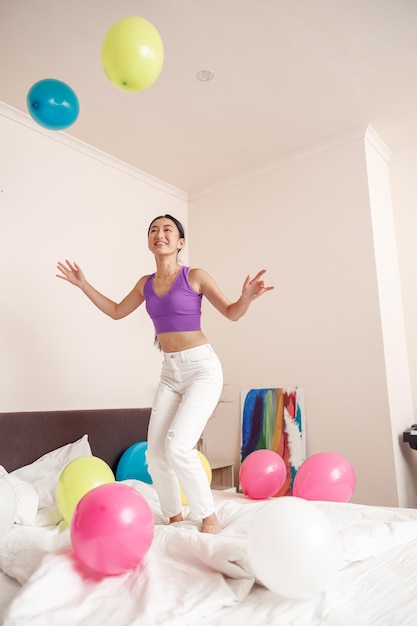 Cheerful young woman jumping on bed at home