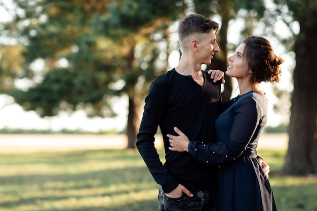 Foto l'uomo e la giovane donna allegra stanno abbracciando all'aperto nel parco estivo.