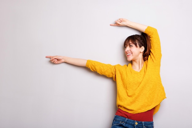 cheerful young woman pointing finger against gray background