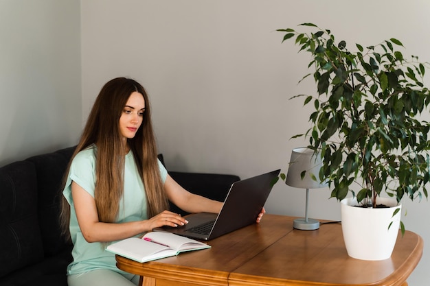 Cheerful young woman programmer works remotely on laptop and\
try to meet deadline at home candid girl with laptop is smiling and\
rejoices at successful work in it company