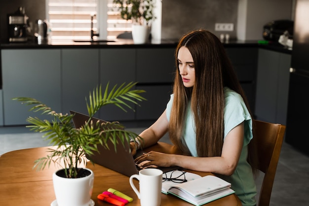 Cheerful young woman programmer works remotely on laptop and
try to meet deadline at home candid girl with laptop is smiling and
rejoices at successful work in it company