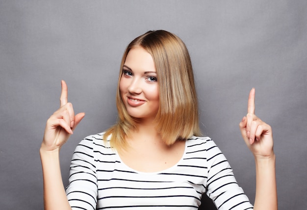 Cheerful young woman showing copyspace, visual imaginary or some