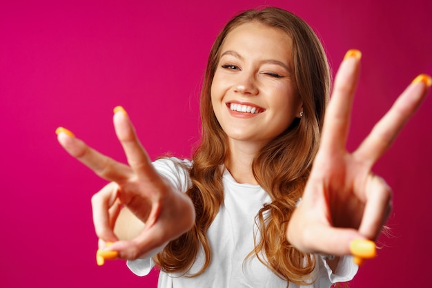 Cheerful young woman showing victory hand sign