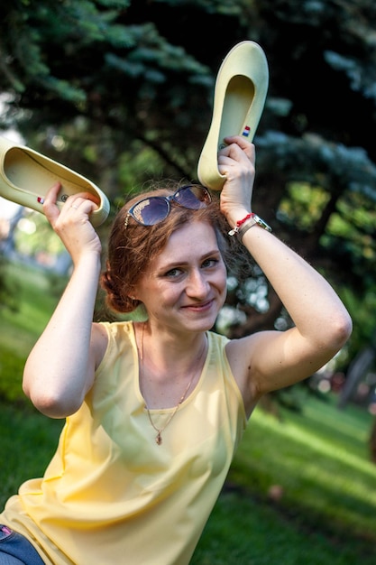 cheerful young woman sits on the lawn in the park summer walk