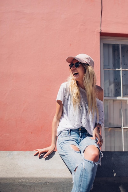 Photo cheerful young woman sitting against wall