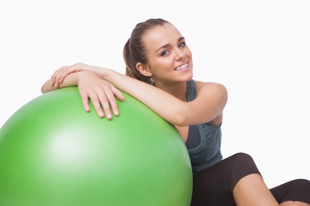 Cheerful young woman sitting next to a fitness ball