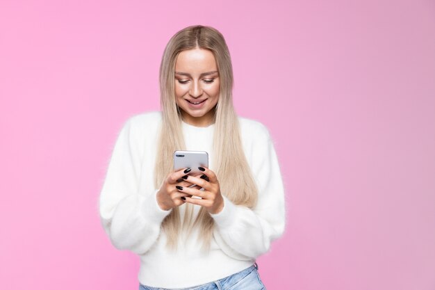 Cheerful young woman smiling and using mobile phone