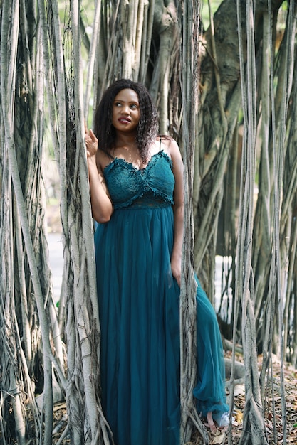 Cheerful young woman standing by tree in the jungle.