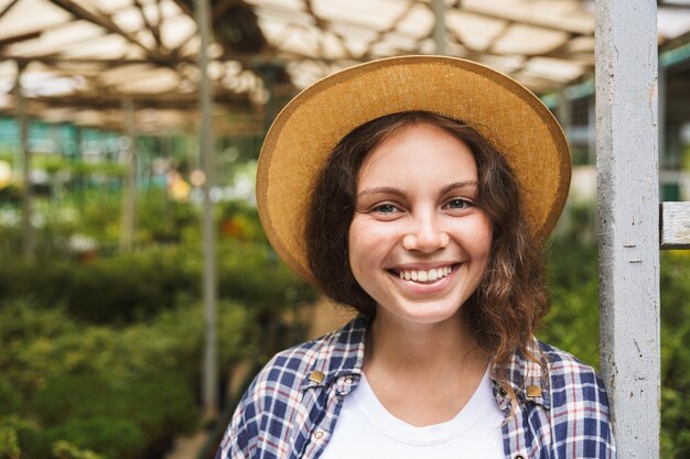 Cheerful young woman standing at a greenhouse