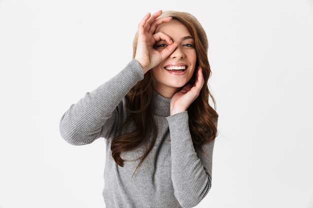 Cheerful young woman standing isolated over white wall, showing ok