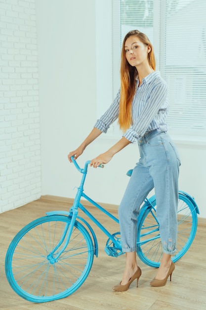 Cheerful young woman standing near bicycle