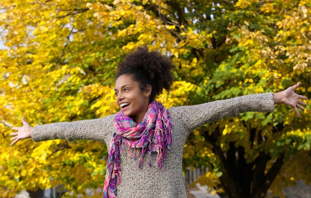 Cheerful young woman standing outdoors with arms outstretched