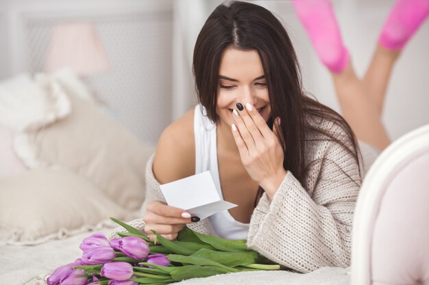 電話で話していると、花を持って陽気な若い女性。チューリップの美しい女性