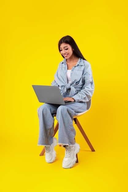 Cheerful young woman using laptop at studio