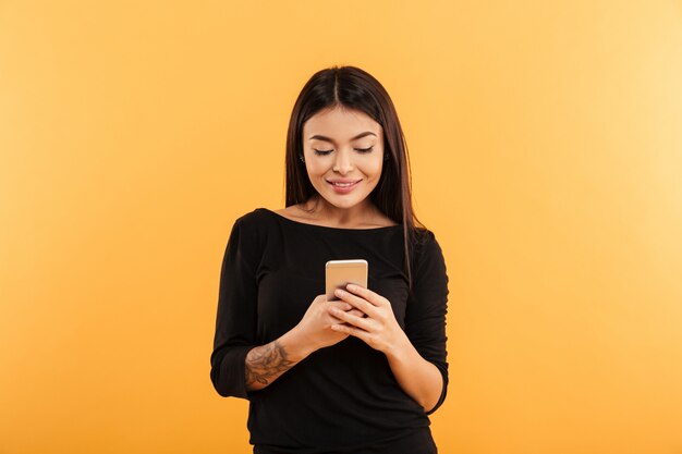 Cheerful young woman using mobile phone.