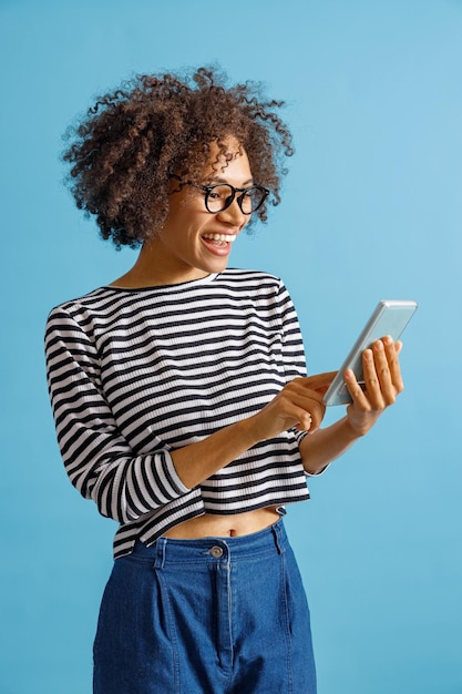 Cheerful young woman using smartphone in studio