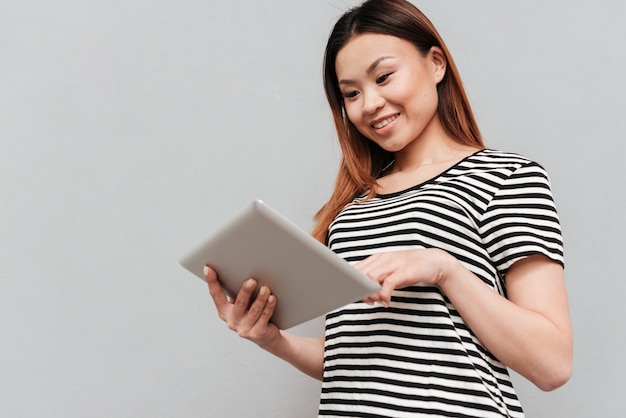 Giovane donna allegra che per mezzo del computer della compressa.