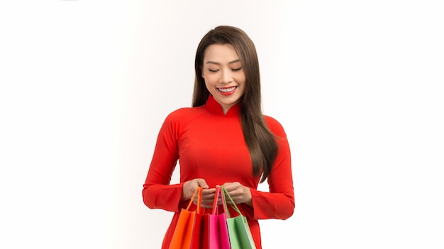 Веселая молодая женщина в платье аозай держит сумки с покупками