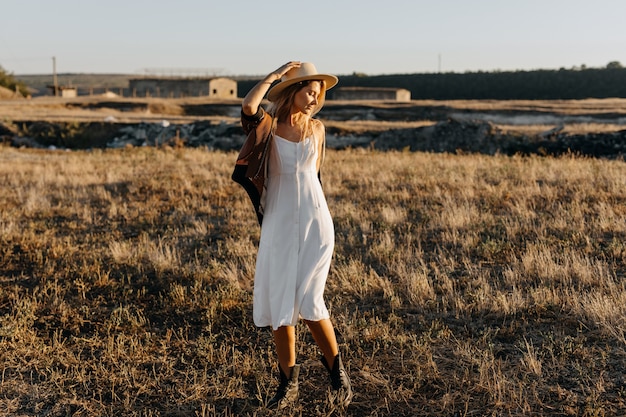 Cheerful young woman wearing a vintage dress and a straw hat at a farm