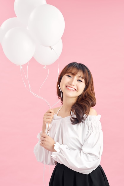 Cheerful young woman with balloons standing and laughing