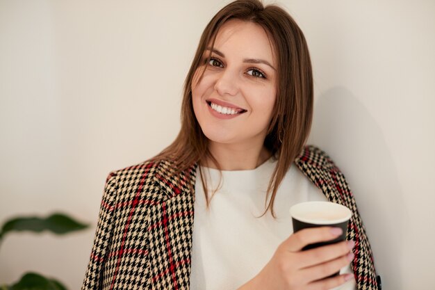 Cheerful young woman with hot drink at cafe