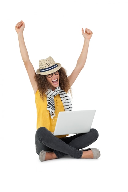 Cheerful young woman with laptop raising hands