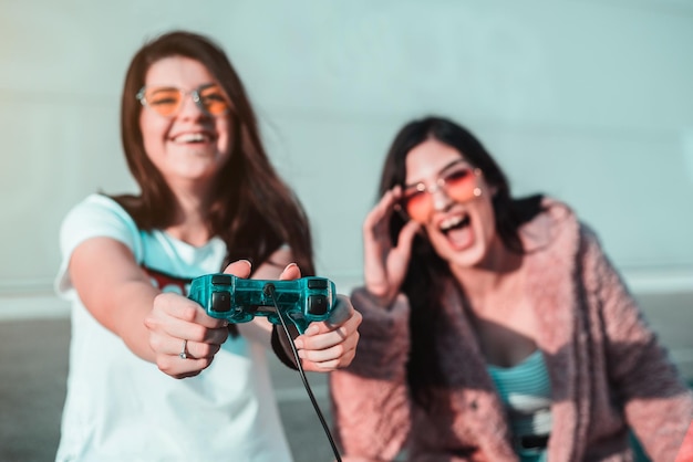 Photo cheerful young women playing with joystick