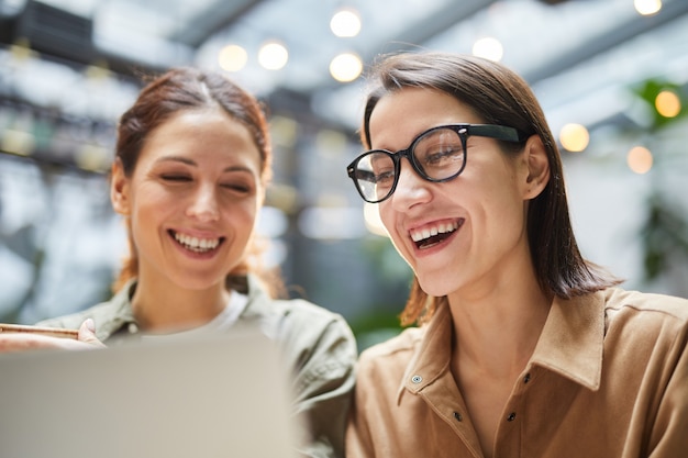 Cheerful Young Women Using Laptop in Cafe