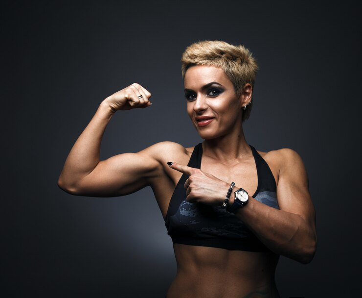 Photo cheerfully smiling sporty woman demonstrating biceps