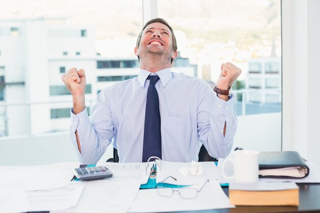 Cheering businessman at his desk 