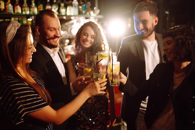 Tifo e bere cocktail gruppo di amici festa in discoteca brindando, drink con cocktail