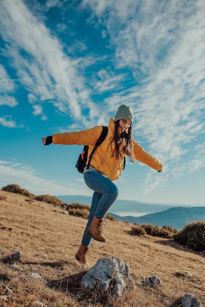 Cheering woman backpacker enjoy the view on sunrise mountain top cliff edge